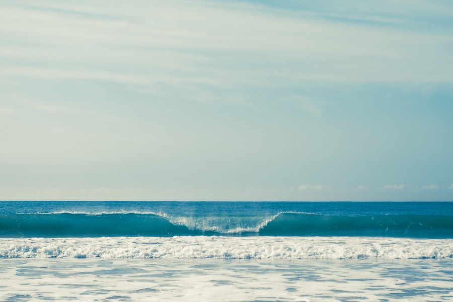Wave breaking with horizon and soft clouds in the background.