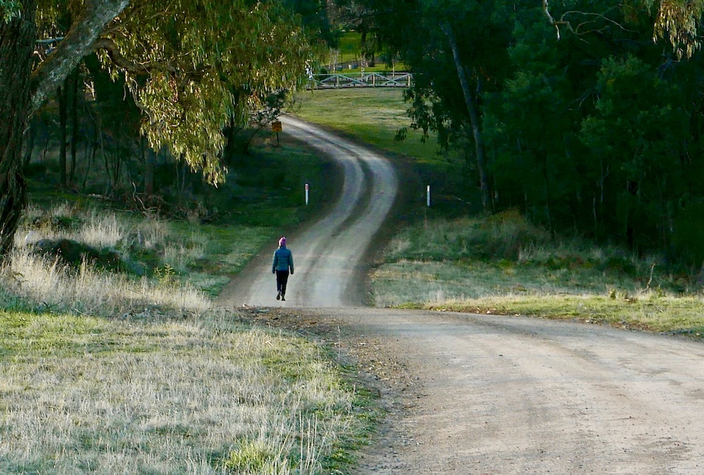 Woman walking along a winding country road.