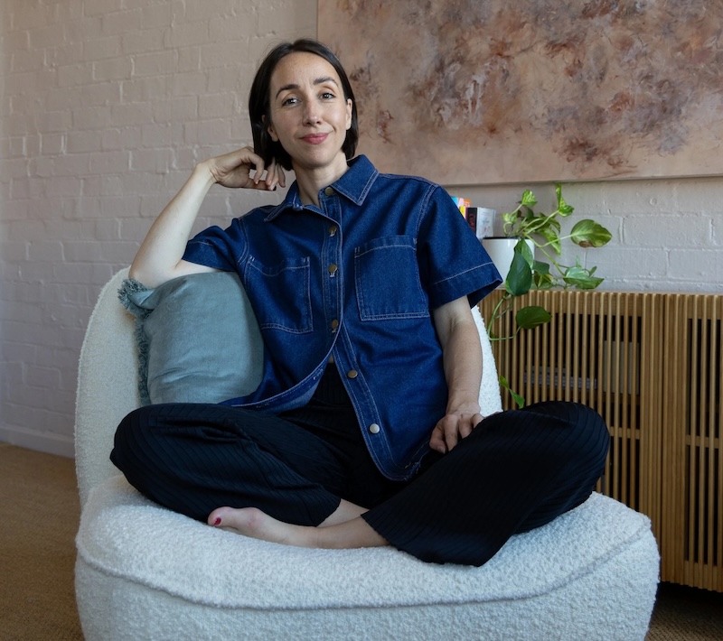 Meg Callander sitting cross legged on a comfortable armchair