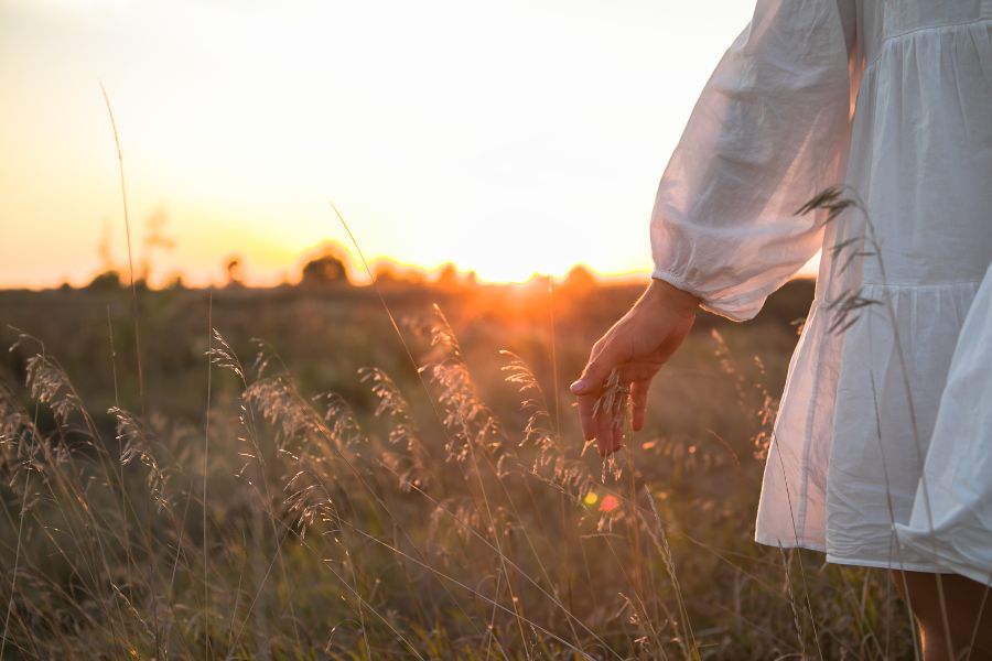 Woman walking through field in late afternoon sun