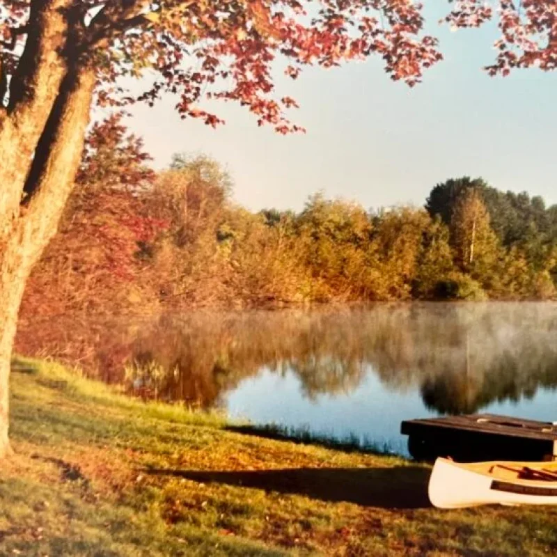 Still lake with mist and autumn colours with a canoe in the foreground