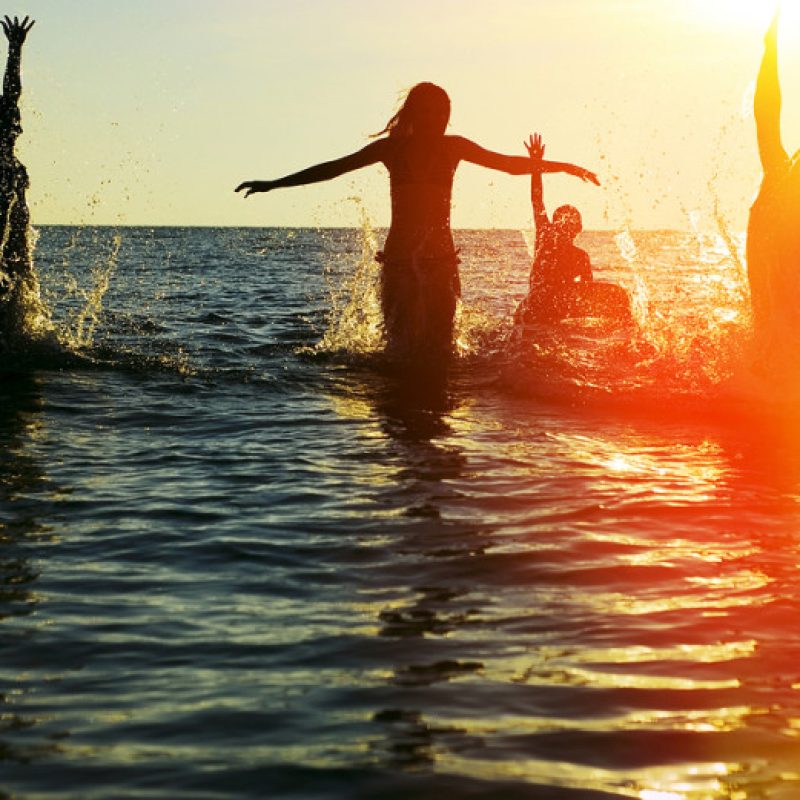 Silhouettes Of People Jumping In Ocean